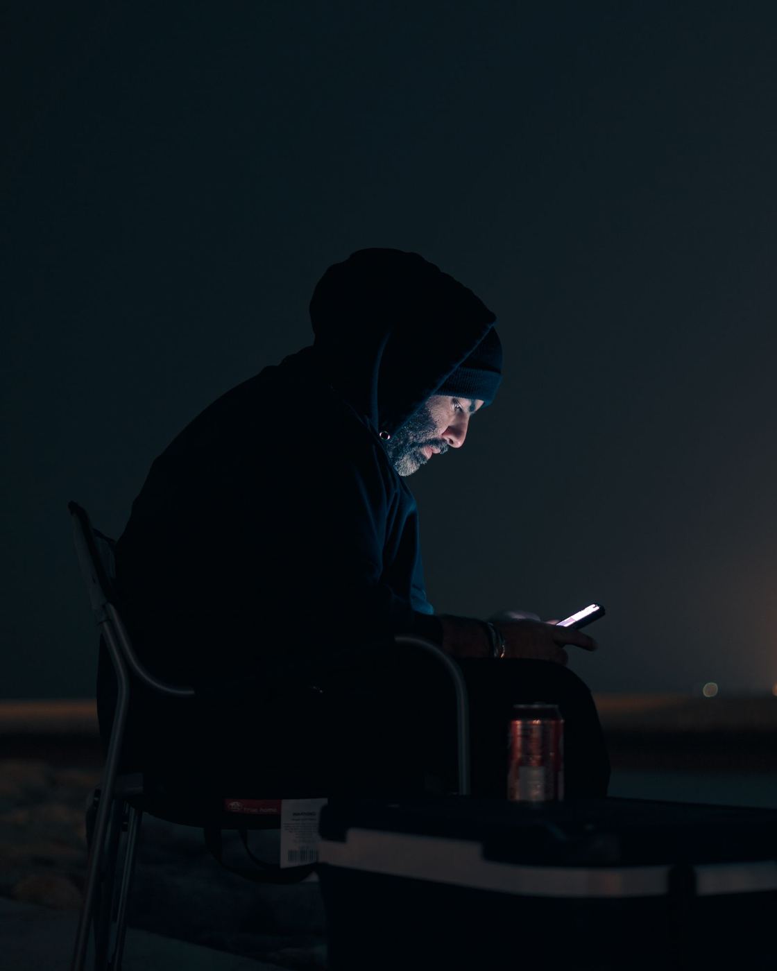Silhouette of a man checking his phone on a dark street